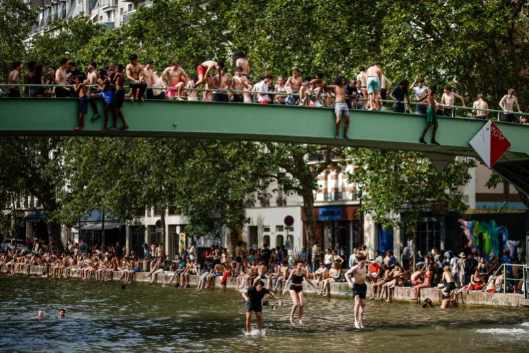 epa13052287 Youths jump from a bridge to cool off in the Canal Saint-Martin, in Paris, France, 20 June 2026. An intense heatwave is gripping Western and Central Europe, pushing temperatures far above seasonal norms for mid-June. EPA/YOAN VALAT