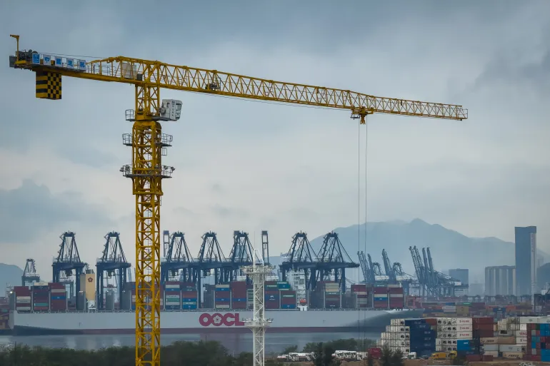 SHENZHEN, CHINA - APRIL 12: A tower crane stands in front of a docked Orient Overseas Container Line (OOCL) cargo vessel at the Yantian International Container Terminal, with gantry cranes lined along the port and container stacks visible in the foreground, symbolizing the dual push for industrial expansion and trade resilience, on April 12, 2025 in Shenzhen, China. China has imposed a new round of retaliatory tariffs on U.S. imports, raising duties to 125% in response to the latest escalation by the United States, which increased tariffs on Chinese goods to 145%. The growing trade tensions have further impacted China's export sector, affecting key industries such as logistics, manufacturing, and cross-border e-commerce. The measures are part of Beijing's broader strategy to counter rising economic pressure and defend its trade interests. (Photo by Cheng Xin/Getty Images)