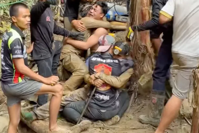 This screen grab made from handout video footage taken on May 30, 2026, and provided by Adisak Wongsoraya, shows two men (centre L and centre R, with headlamp) being hugged after they were rescued from a semi-submerged cave in Laos' central Xaysomboun province, northeast of the capital Vientiane. Four more men trapped in a semi-submerged Laos cave for 10 days were freed on May 30, rescuers said, after one was successfully brought to the surface a day earlier, but two remained missing. (Photo by Handout / Adisak Wongsoraya / AFP) / RESTRICTED TO EDITORIAL USE - MANDATORY CREDIT "AFP PHOTO/ Adisak Wongsoraya" - NO MARKETING NO ADVERTISING CAMPAIGNS - DISTRIBUTED AS A SERVICE TO CLIENTS - NO ARCHIVE