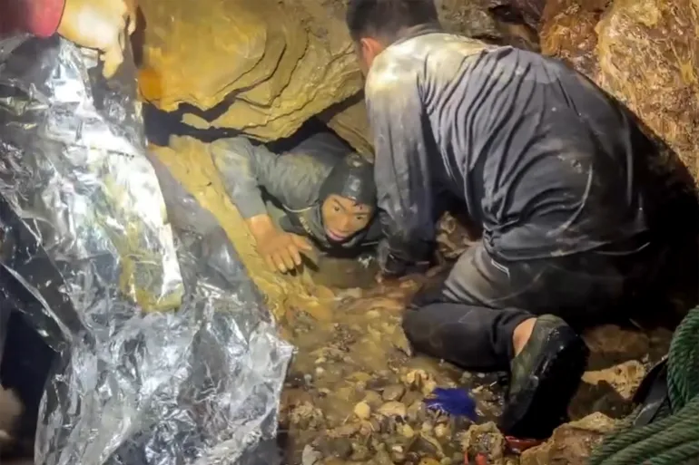 This screengrab made from handout video footage taken on May 29, 2026, and provided by Metta Tham Rescue Kalasin, shows a rescue team freeing one of seven men (L) trapped inside a semi-submerged cave in central Xaysomboun province, northeast of the capital Vientiane. A rescue team freed on May 29 one of seven men trapped inside a semi-submerged cave in Laos for more than a week, the group working at the site said. (Photo by Handout / Metta Tham Rescue Kalasin / AFP) / RESTRICTED TO EDITORIAL USE - MANDATORY CREDIT "AFP PHOTO/ HO/ Metta Tham Rescue Kalasin - NO MARKETING NO ADVERTISING CAMPAIGNS - DISTRIBUTED AS A SERVICE TO CLIENTS - NO ARCHIVE