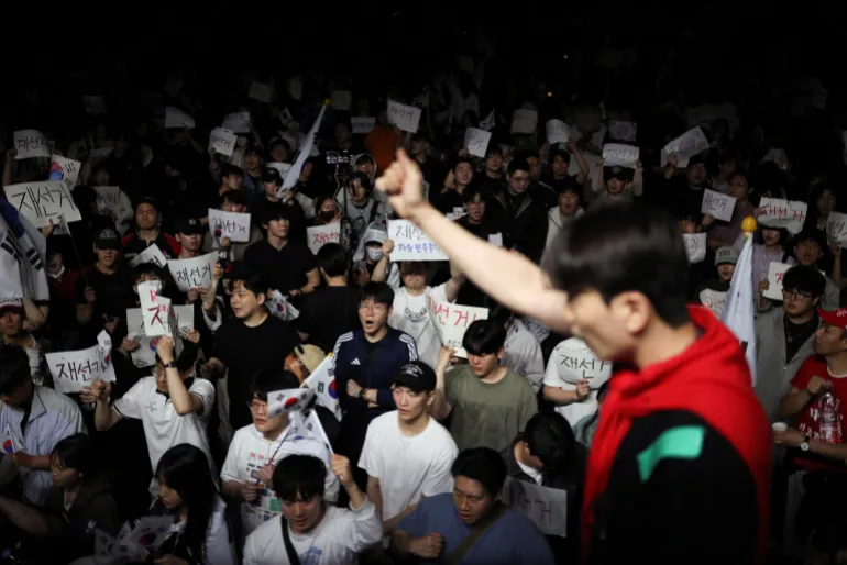 A demonstrator raises his fist as people surround a vote-counting centre to protest a controversy over a shortage of ballot papers that disrupted voting in the local election and to call for a rerun of the election, in Seoul, South Korea, June 6, 2026. REUTERS/Kim Hong-Ji