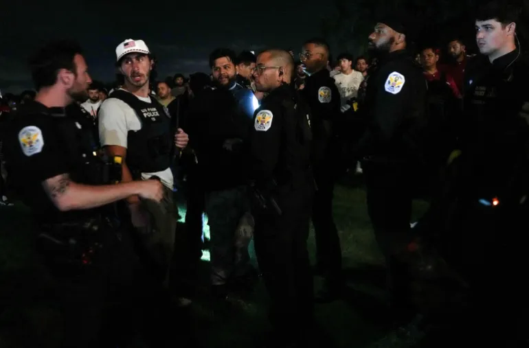Law enforcement agents detain a man as fans watch a match during UFC Freedom 250 from a street across the Ellipse next to the Washington Monument, in Washington, D.C., U.S., June 15, 2026. REUTERS/Leah Millis REFILE - ADDING EVENT NAME