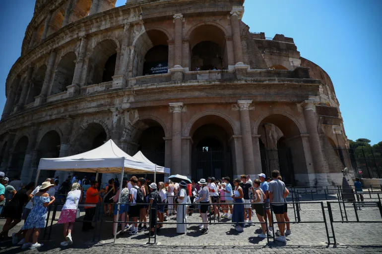 Visitors use umbrella for shade as they queue at the entrance to the Colosseum during a heatwave in Rome, Italy, June 20, 2026. REUTERS/Guglielmo Mangiapane